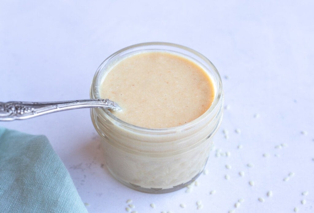 Sesame Tahini paste in a small jar with a spoon 