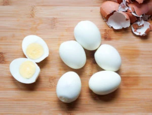 Peeled eggs on a wooden board with one egg cut in half