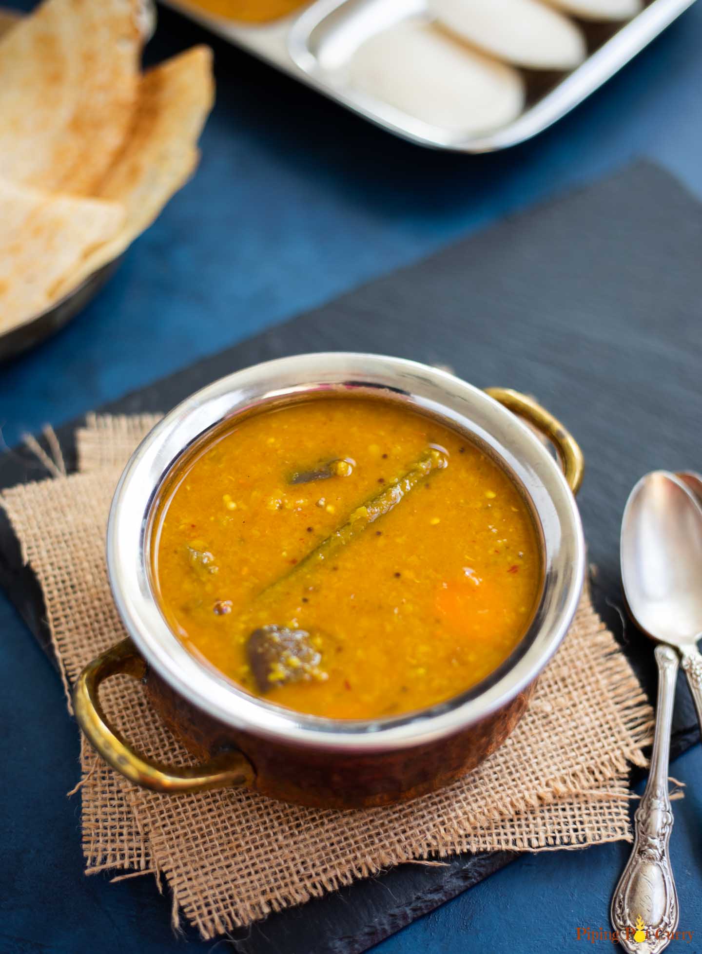 Vegetable Sambar in a bowl with idli and dosa in the back