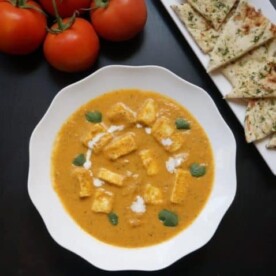Instant Pot Paneer Butter Masala topped with cilantro and cream with naan bread on the side