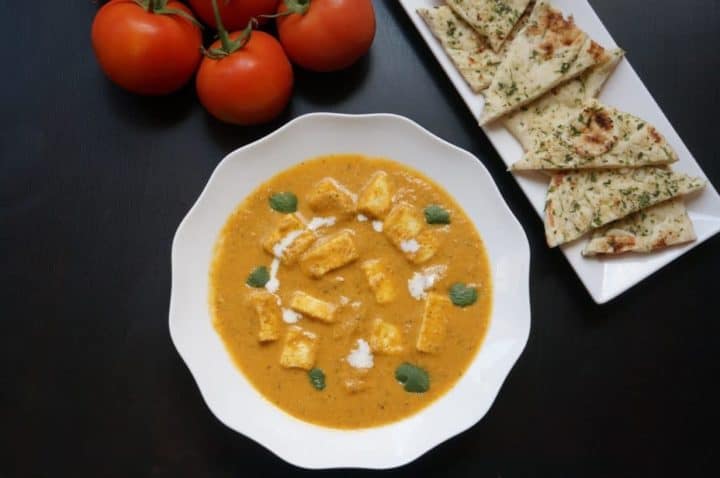 Instant Pot Paneer Butter Masala topped with cilantro and cream with naan bread on the side