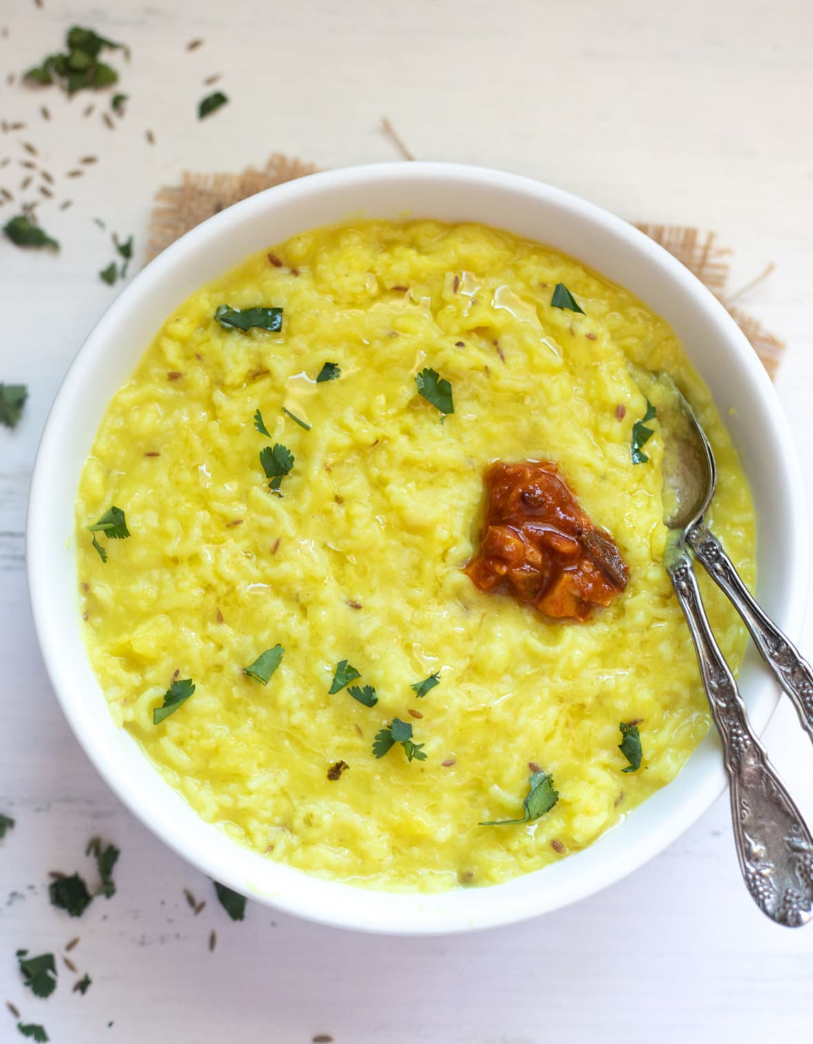 Moong Dal Khichdi in a bowl garnished with cilantro and topped with pickle