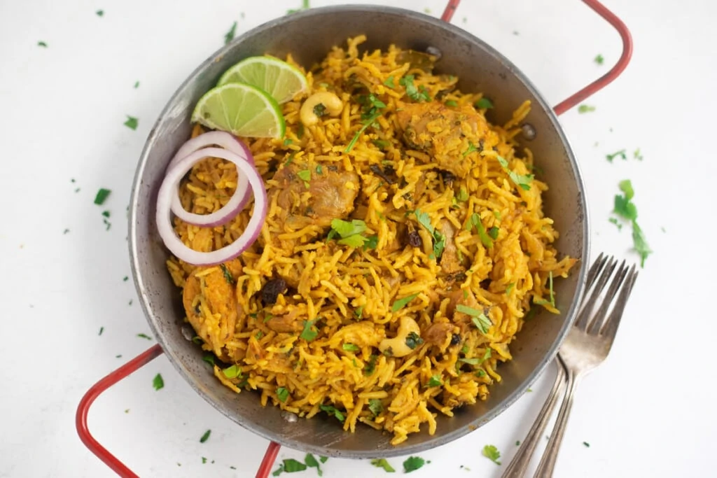 Chicken Biryani served in a platter garnished with onions and limes