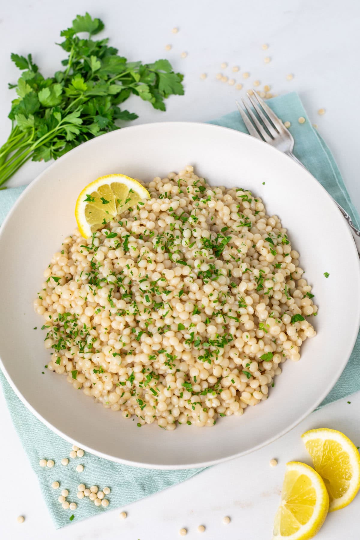 Instant Pot Pearl Couscous on a white plate topped with parsley