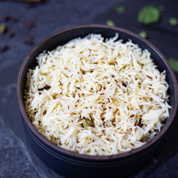 Jeera Rice with a cardamom in a black bowl