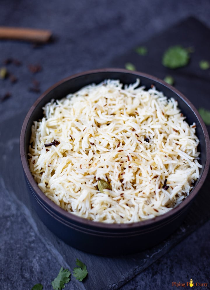 Jeera Rice with a cardamom in a black bowl