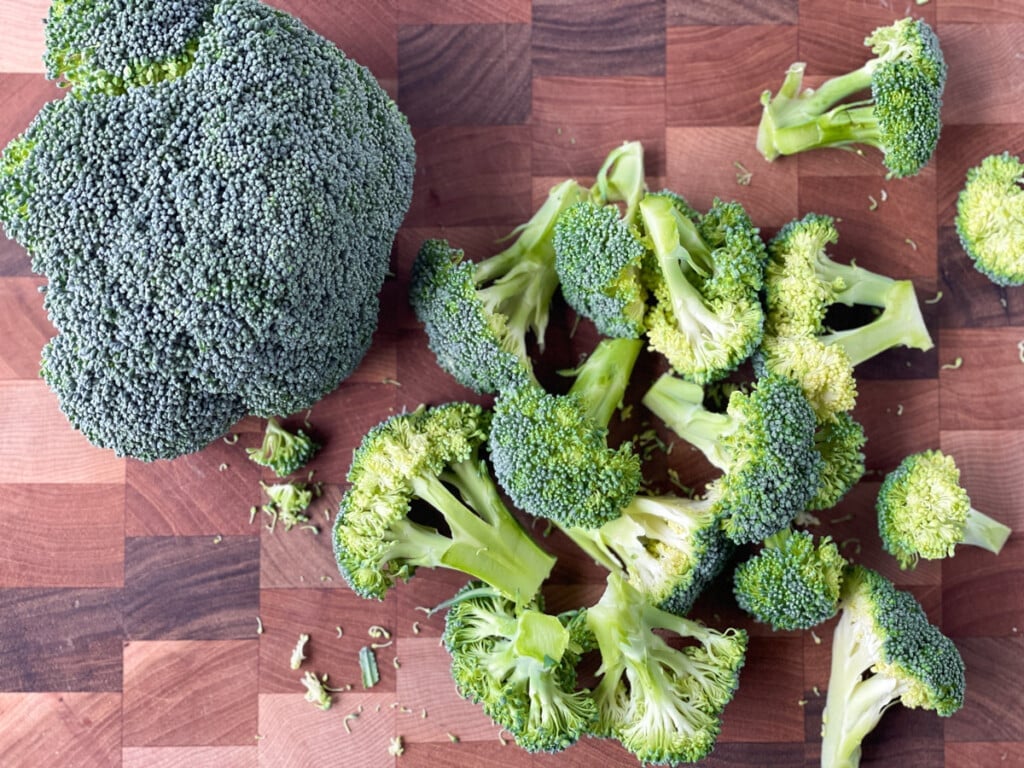 A head of broccoli along with some chopped florets