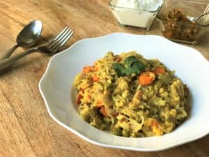 Instant Pot Masala Khichdi in a white bowl along with yogurt and pickle.