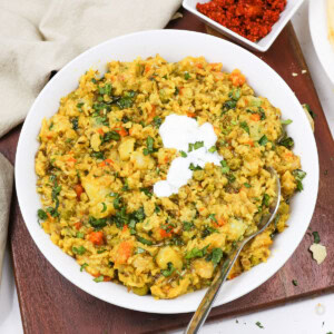 Masala khichdi in a white bowl topped with yogurt