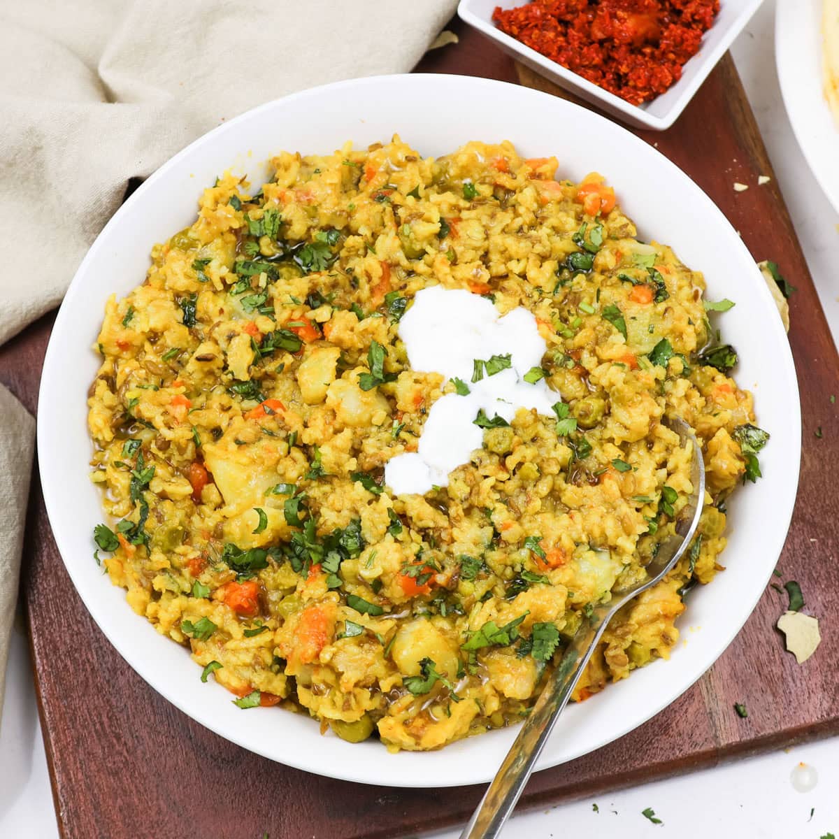 Masala khichdi in a white bowl topped with yogurt