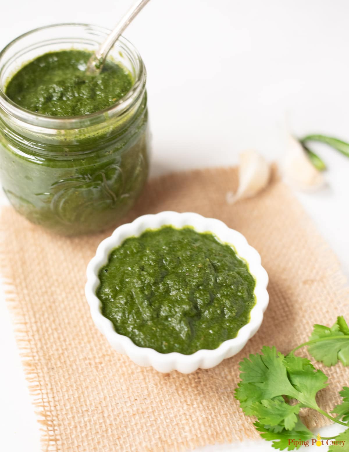 Green mint chutney in a white bowl and in a glass jar to store