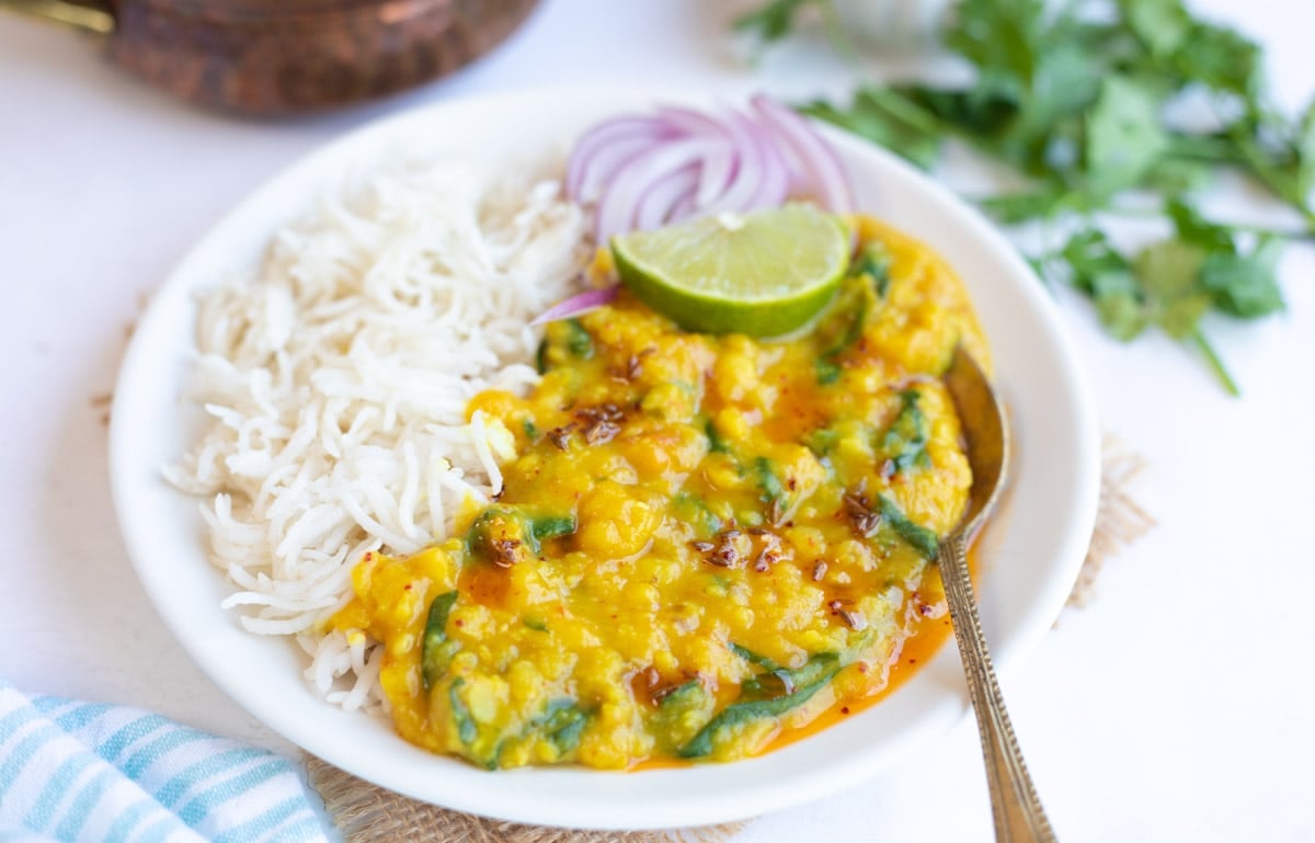 spinach dal served with rice in a white plate