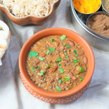 Dal Makhani made in the instant pot, served in a earthen pot with some brown rice and spices in the back
