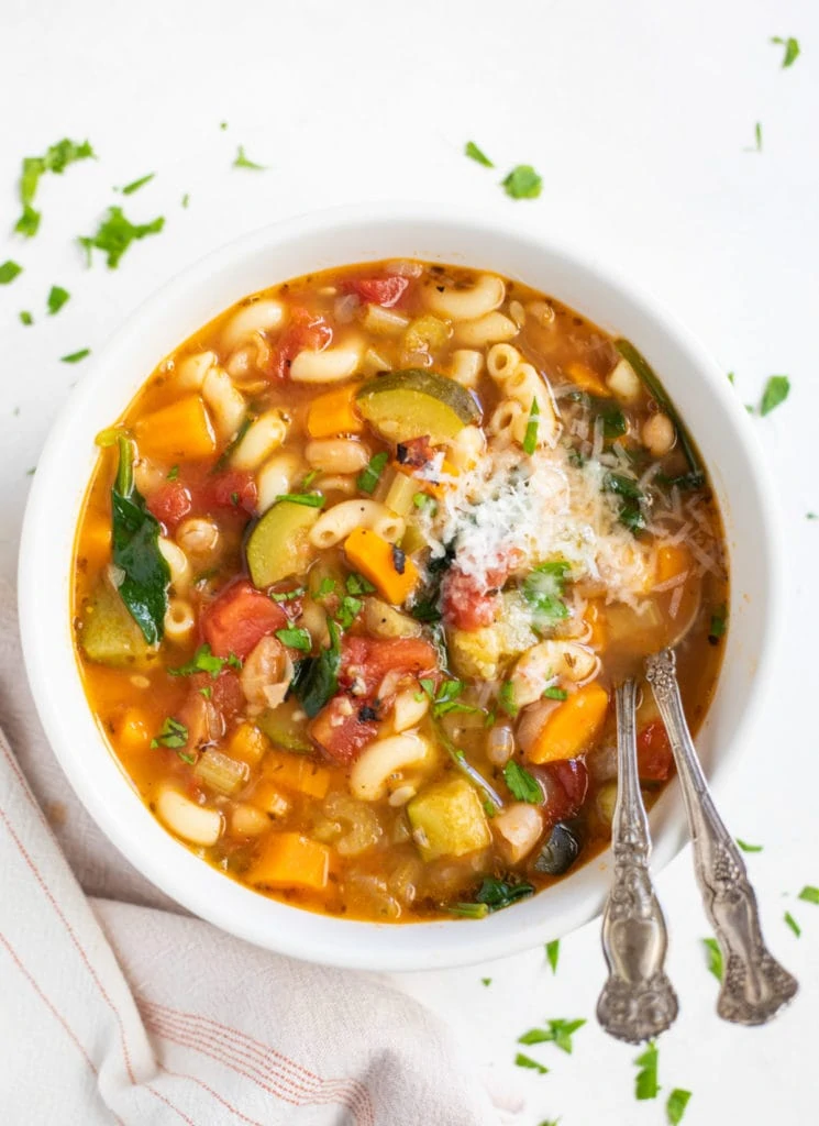 Minestrone soup in a white bowl topped with parmesan