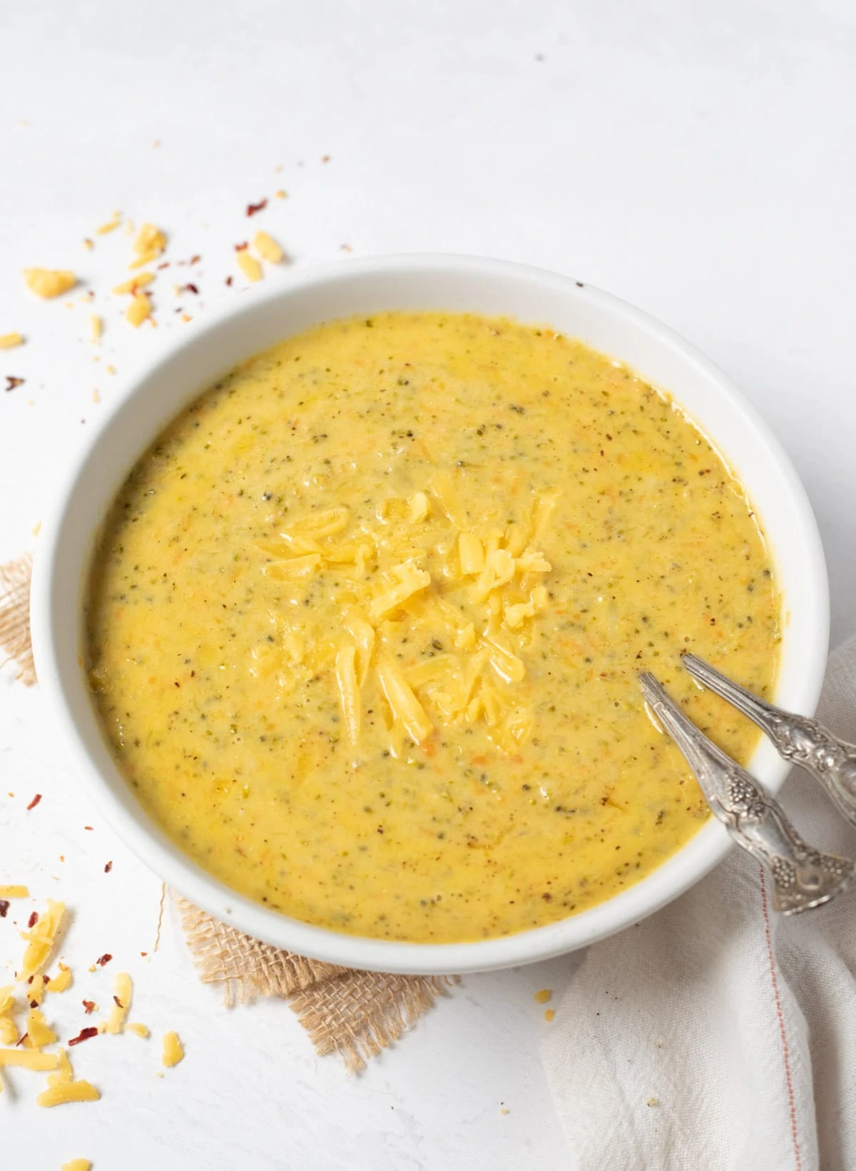 Broccoli Cheddar Soup topped with grated cheese in a white bowl