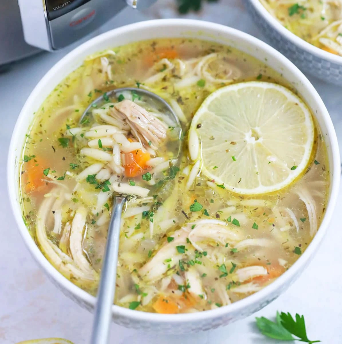 Lemon Chicken orzo soup made in instant pot served in a bowl topped with a spice of lemon