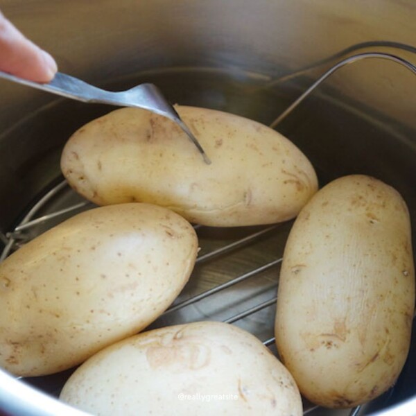 Boiled potatoes in instant pot poking with fork to check doneness