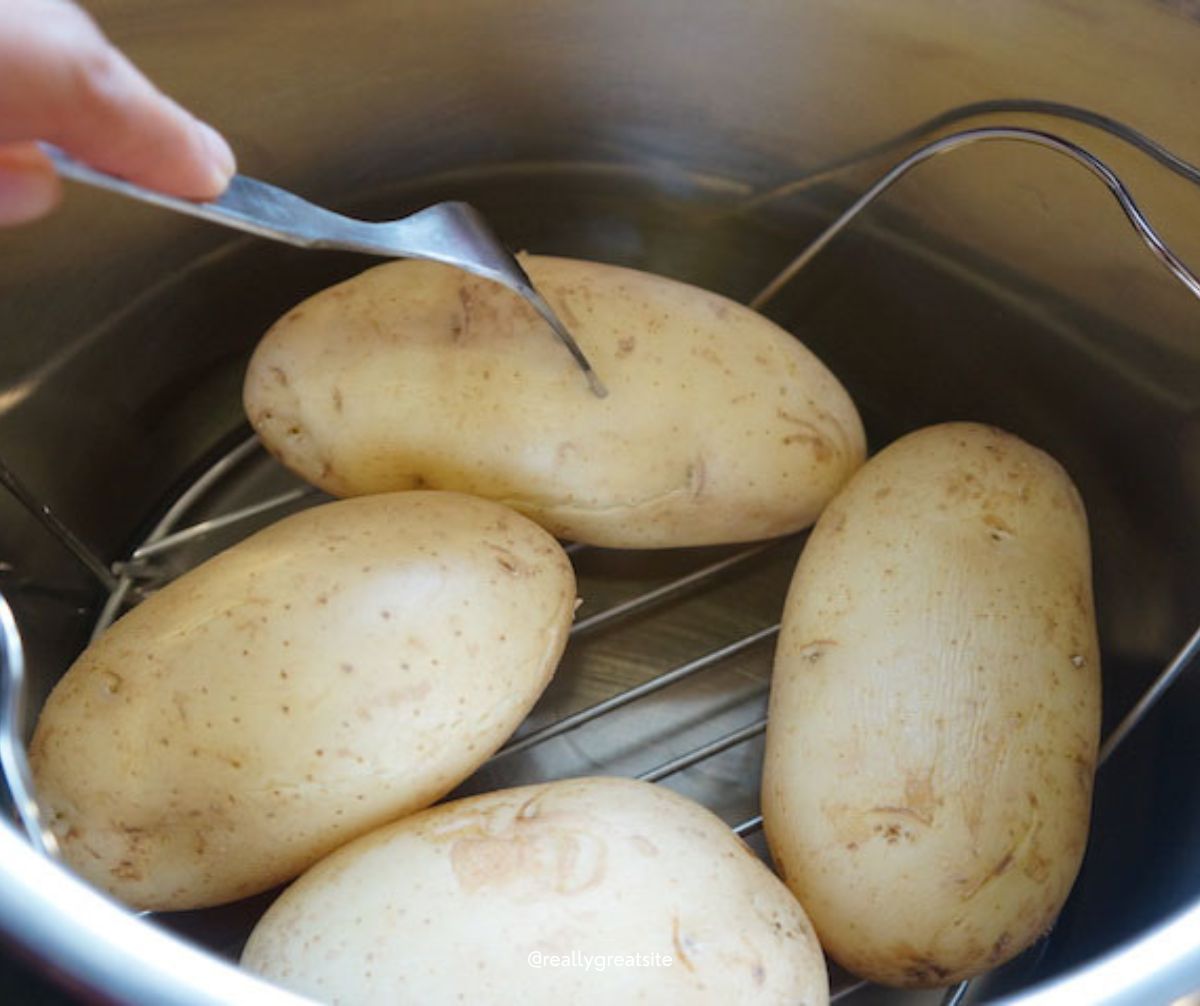 Boiled potatoes in instant pot poking with fork to check doneness