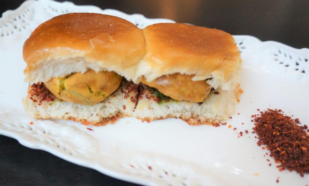 Vada Pav is the humble street food of Mumbai. A fried potato fritter in chickpea batter or vada, is stuffed in between mini-burger buns called pav, along with sweet and spicy sauces or chutney.
