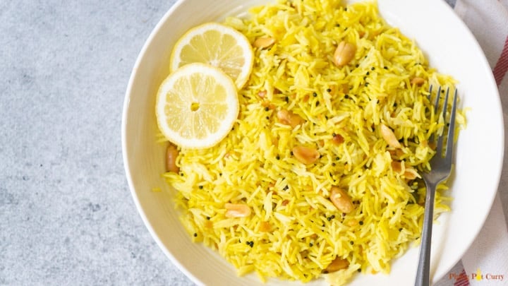 Instant Pot Lemon Rice in a white bowl with peanuts and sliced lemon. 