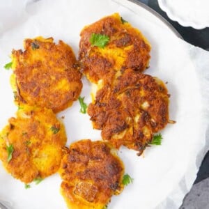 Vegan Chickpea Squash Fritters in a plate with yogurt dip on the side