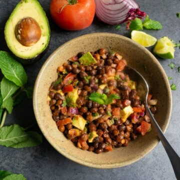 Kala Chana Chaat. Black Chickpea Salad in a bowl with avocado, tomato, onion, mint and lime pieces