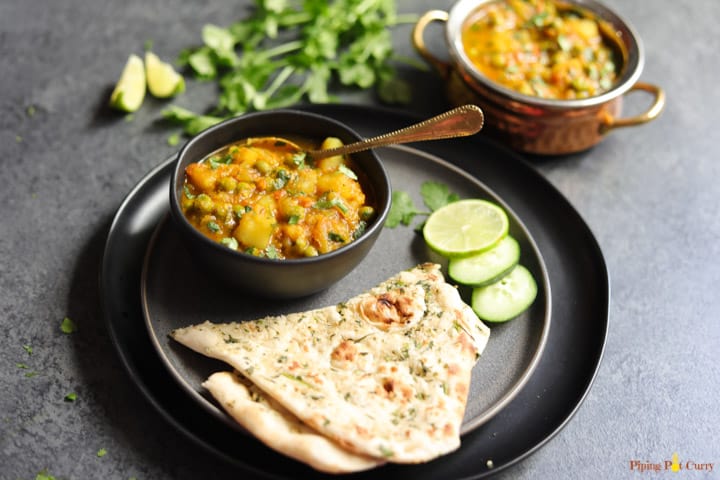 Aloo Matar made in instant pot served in a bowl, with naan bread on the side