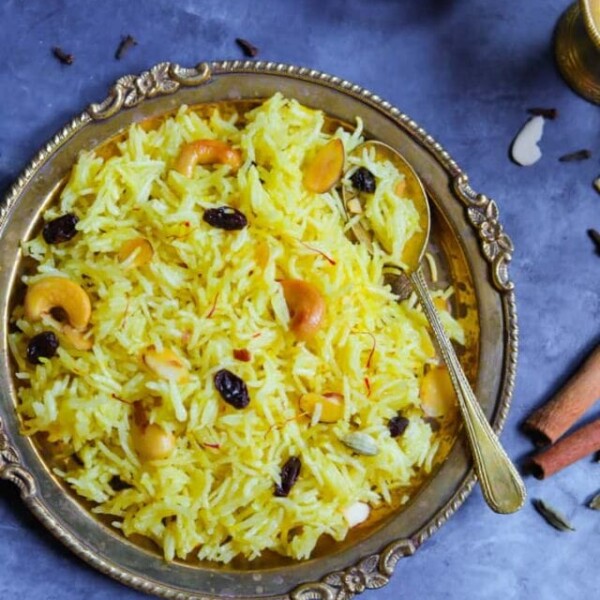zarda sweet rice topped with nuts and raisins in a bronze plate