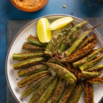 Bharwa Bhindi (Stuffed Okra) served in a plate with lemon wedges and the stuffed spices on the side.