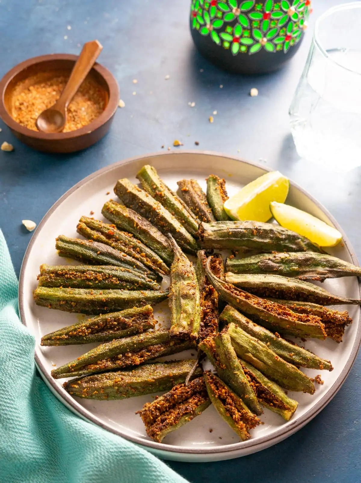 Bharwan Bhindi (Stuffed Okra) served in a plate with lemon wedges and the stuffed spices on the side.