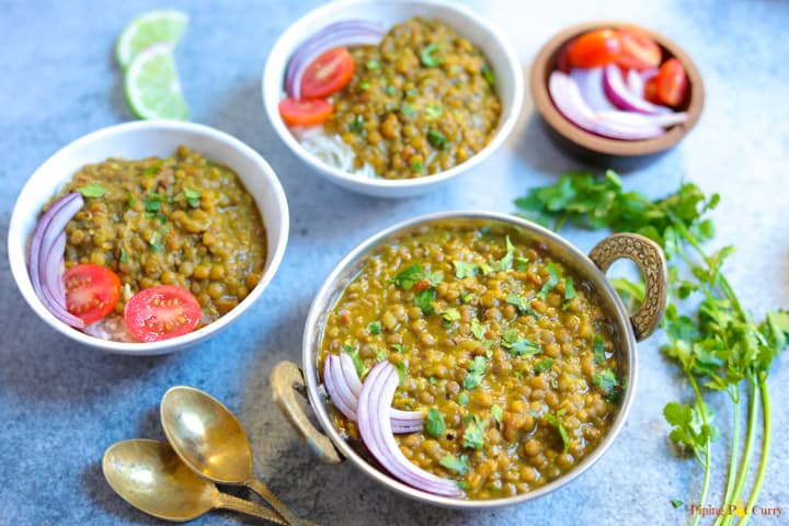 Masoor Dal made in instant pot served over rice in two bowls along with onions, tomato and rice