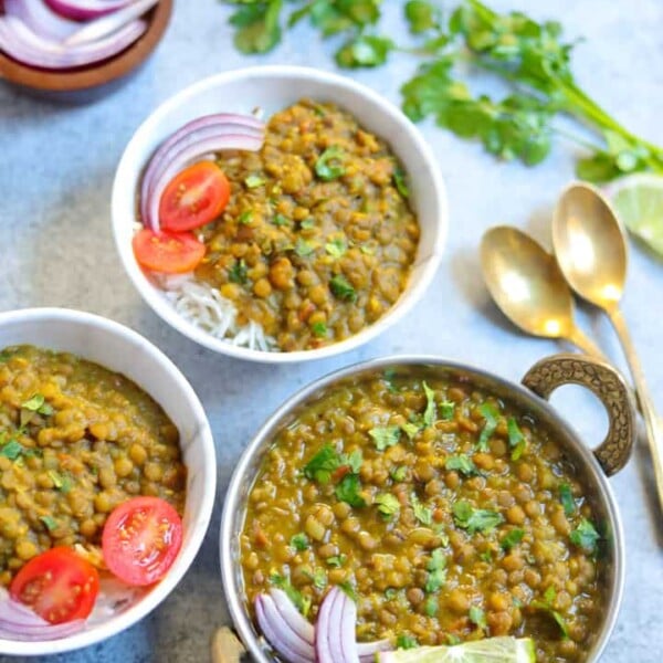 Masoor Dal made in instant pot served over rice in two bowls along with onions, tomato and rice