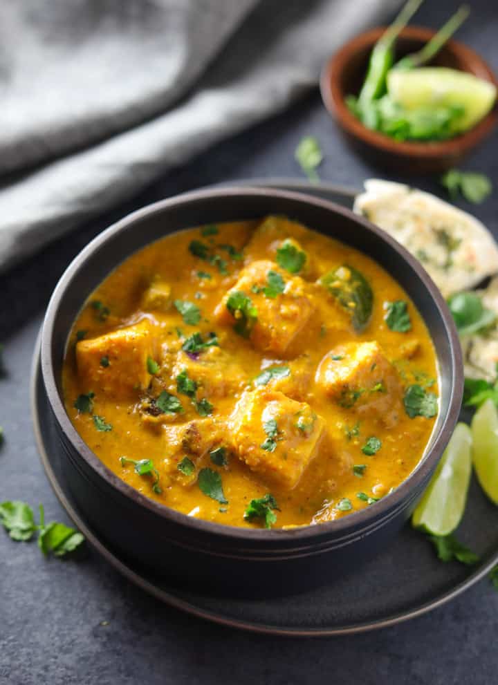 Paneer Tikka Masala made in Instant Pot served in a bowl with some naan and limes on the side.