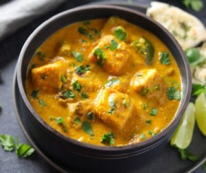 Paneer Tikka Masala made in Instant Pot served in a bowl with some naan and limes on the side.