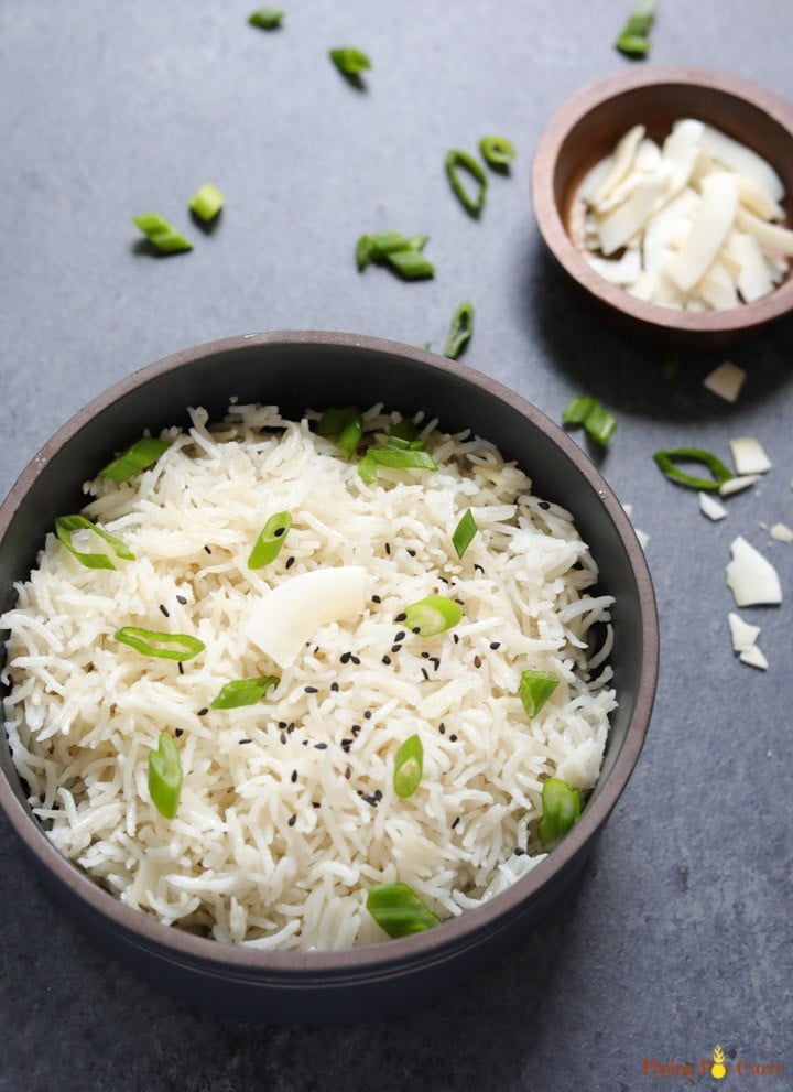 Coconut Rice made in the pressure cooker served in a black bowl topped with sesame seeds and scallions