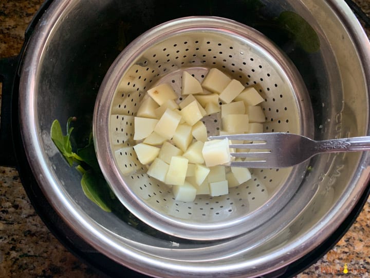 Showing a potato cube steamed along with spinach to make saag aloo