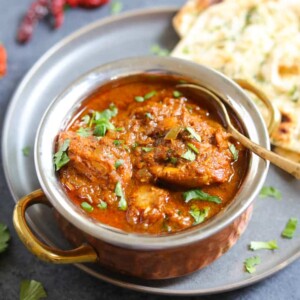 Chicken Vindaloo served in a bowl along with naan bread.
