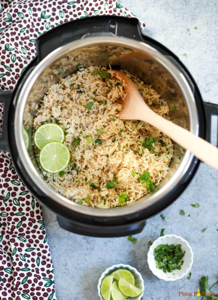 Cilantro Lime Brown Rice cooked in the instant pot, with a ladle and some lime and cilantro in small white bowls
