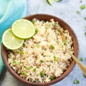 Instant Pot Cilantro Lime Brown Rice served in a brown bowl with lime slices and a spoon