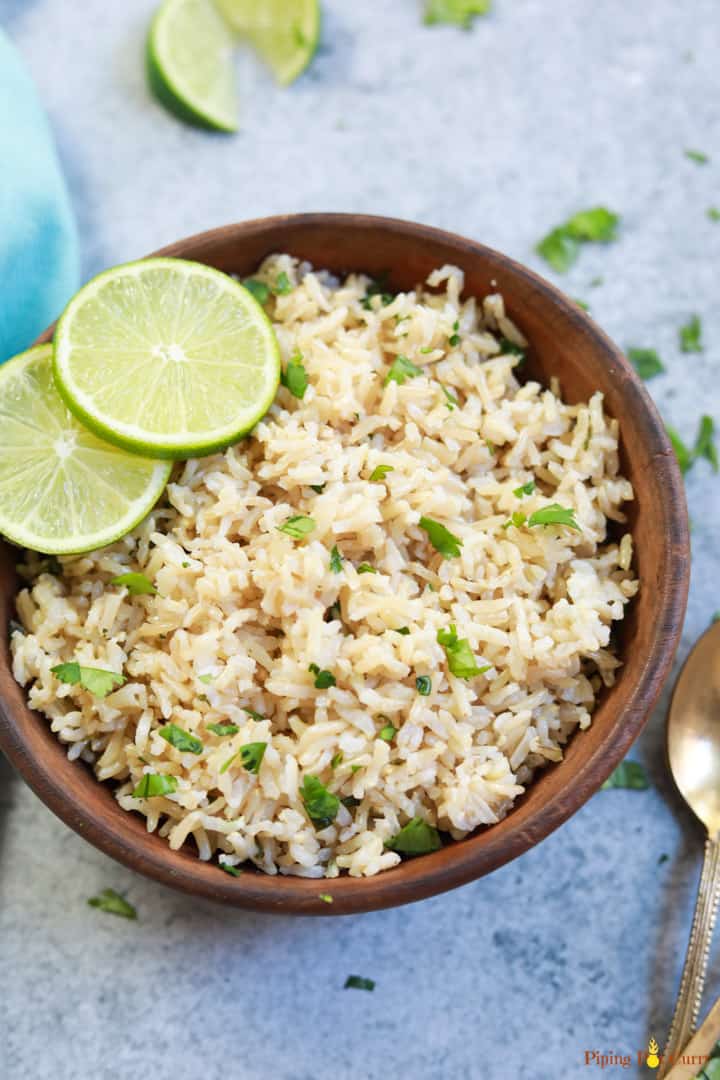 Instant Pot Cilantro Lime Brown Rice served in a brown bowl with lime slices and a spoon