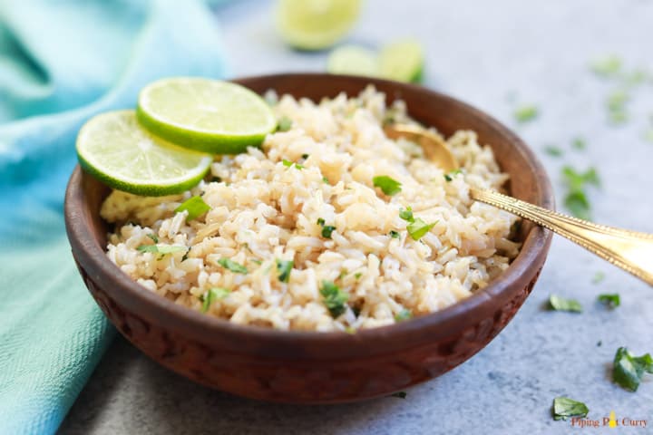 Pressure Cooker Cilantro Lime Brown Rice served in a brown bowl with lime slices and a spoon
