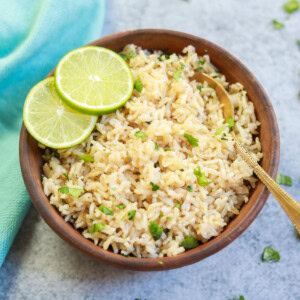 Instant Pot Cilantro Lime Brown Rice served in a brown bowl with lime slices and a spoon