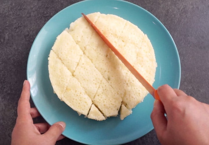 Rava Dhokla Instant Pot - Piping Pot Curry-9 Suji Dhokla on a plate being cut into pieces with a large knife