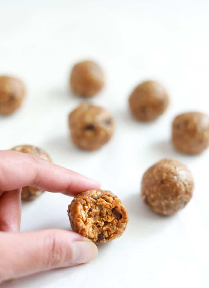 A half eaten Almond Butter Energy Ball closeup, with many more almond balls in the back