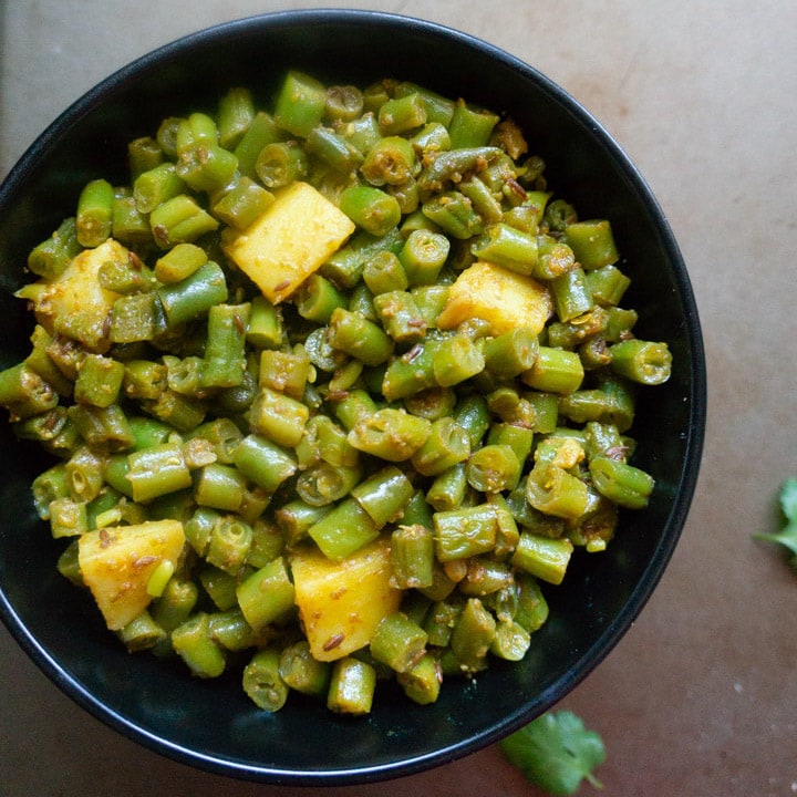 Beans and potato stir fry in a black bowl