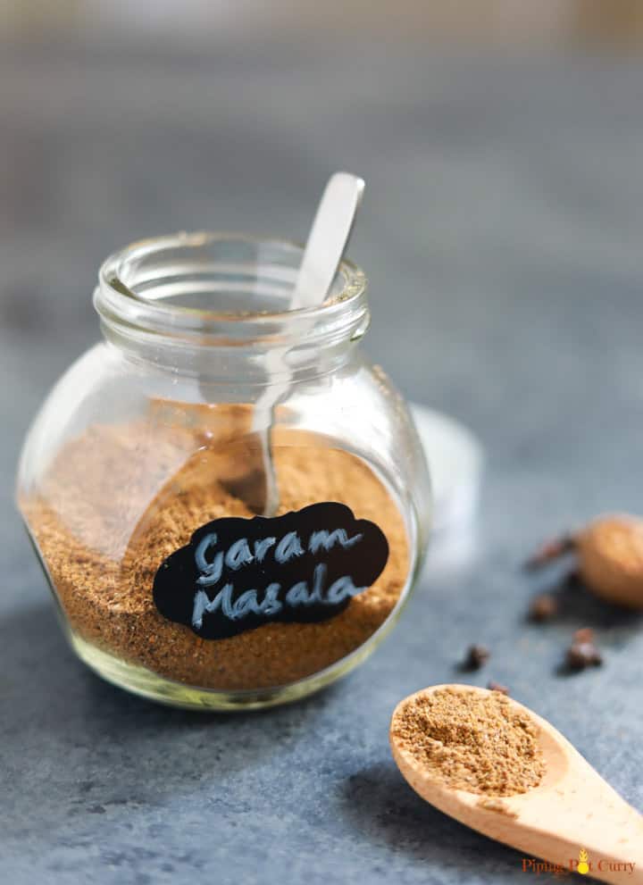 Homemade Garam Masala powder in a glass bottle with a spoon