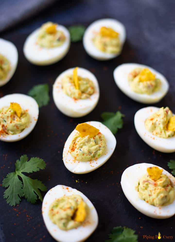 Guacamole Deviled Eggs on a black base with cilantro spread around