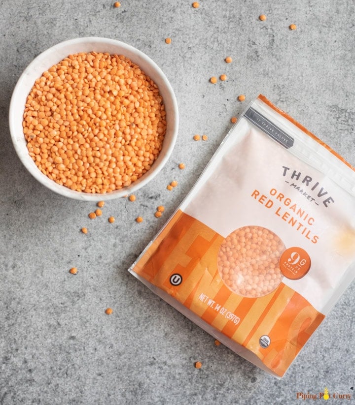 Red lentils in a bowl along with a packet of red lentils from Thrive Market