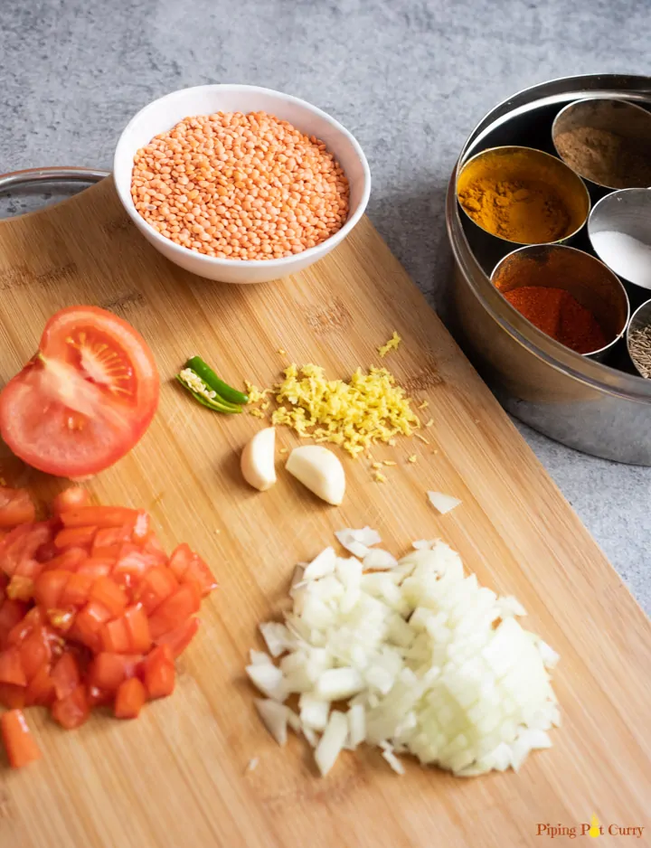 Ingredients to cook dal - onions, tomatoes, ginger, garlic, spices, red lentils