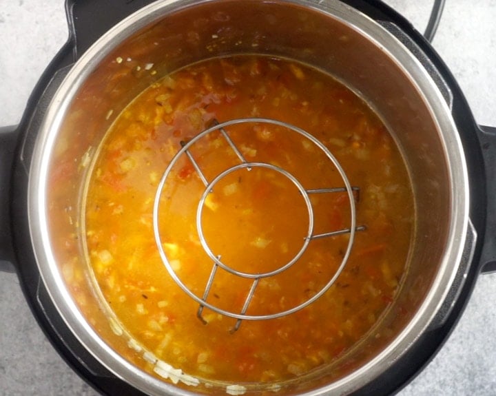 Trivet kept on top of red lentils ready to be cooked in instant pot